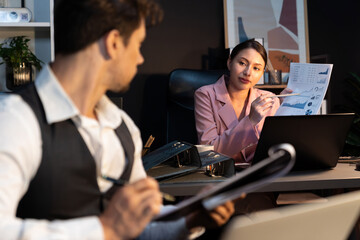 Focusing on sitting on pink suit woman presenting graph target on paperwork to explain customer market target graph report's business expansion to coworker while man holding paper to sign. Postulate.