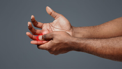 Cropped of man suffering from pain in hand and massaging his painful finger, white background