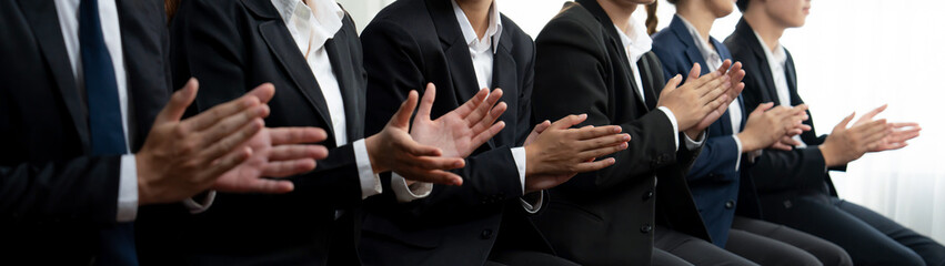 Obraz premium Business people gather in line at corporate event to applaud achievement and celebrate company's success on motivation speech or business presentation meeting with audience in panorama banner. Shrewd