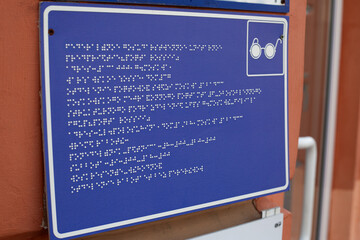 Sign with information in braille text for blind people in front of the building entrance....