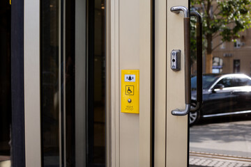 Modern panel with help button for people with disabilities near building door, sign with wheelchair...
