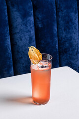 An alcoholic cocktail in a highball collins glass garnished with physalis served with ice
