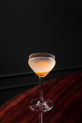 An alcoholic cocktail in coupe glass with apricot garnish