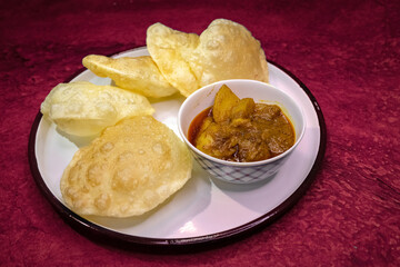 Bengali traditional and most common breakfast or snack 'Luchi' or 'Poori' or deep-fried flatbread with spicy potato curry, served in earthenware