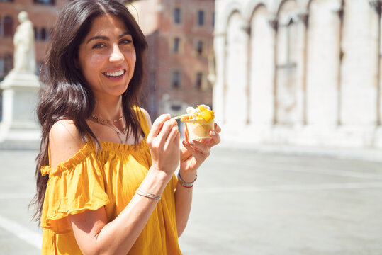 Fototapeta Beautiful smiling woman eating traditional italian ice cream on the street in Italy 