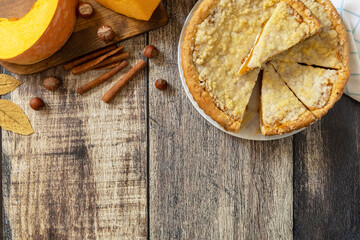 Fall traditional pumpkin pie with cinnamon on a rustic wooden background.