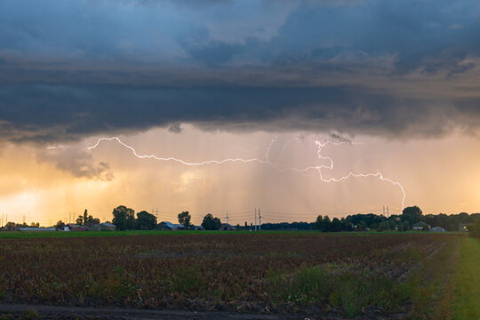 Lightning bolts below the base of an autumn thunderstorm at sunset