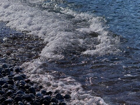 Sea waves foam on pebbles seashore