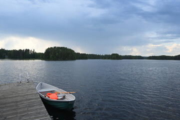 Naklejka premium A boat at the dock on the lake in Finland. Typical Finnish landscape with a lake and boat