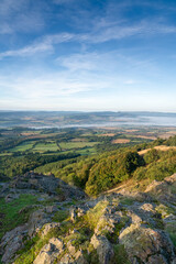 Naklejka premium A view of misty countryside in Shropshire, UK with a rocky foreground taken from the summit of the Wrekin hill in portrait orientation
