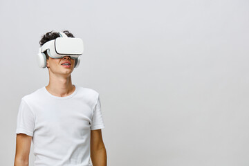 young man wearing virtual reality headset and headphones, smiling while experiencing immersive technology against neutral background