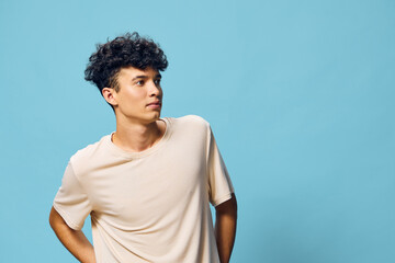 Portrait of a young man with curly hair against a bright blue background, exuding a relaxed and thoughtful vibe, dressed casually in a beige t shirt, perfect for lifestyle imagery