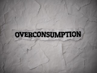 Crumpled piece of paper with words Overconsumption  on a torn white paper pieces background.