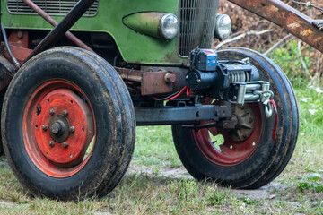 Close-up of a vintage tractor's front wheels, showcasing the rustic design and details of the machinery in a natural setting.