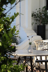 espaco externo do bistro com mesas ao ar livre, decorado com cadeiras de madeira, vasos de flores em meio a sombra das plantas do jardim