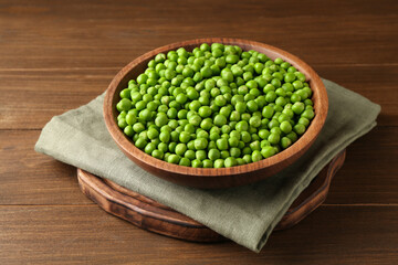 Fresh green peas in bowl on wooden table