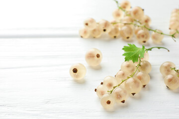 Fresh white currant berries and green leaf on white wooden table, closeup. Space for text