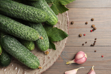 Fresh green cucumbers and spices on wooden table, flat lay
