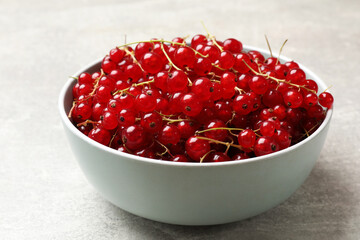 Fresh red currants in bowl on light grey table, closeup
