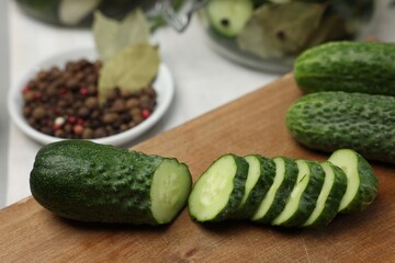 Board with fresh cut cucumber and spices on light table, closeup. Preparation for pickling