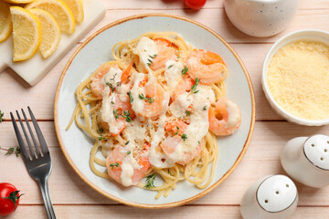 Tasty pasta with shrimps, creamy sauce and cheese on light wooden table, flat lay
