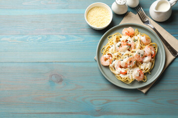Delicious pasta with shrimps served on blue wooden table, flat lay. Space for text