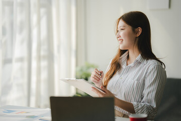 Businesswoman is calculating annual income and expenses at her office. Smiling female employee using laptop in modern office Copy space