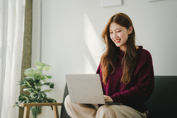 Fototapeta premium Smiling young woman uses social media to relax at home on the weekend. Relaxation concept