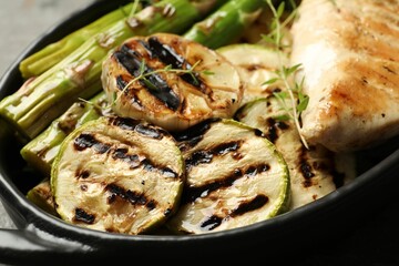 Delicious grilled vegetables and chicken breast in baking dish on table, closeup