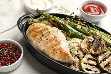 Delicious grilled vegetables and chicken breast in baking dish on white wooden table, closeup