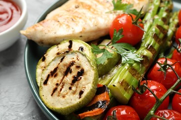 Delicious grilled vegetables and chicken breast on table, closeup