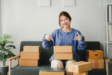 Small online business owner smiling The seller is checking the parcel and packing the product before sending. Preparing packages for SME e-commerce delivery service concepts