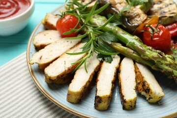 Delicious grilled vegetables and cut chicken meat served with sauce on light blue table, closeup