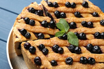 Cut homemade blueberry pie on blue wooden table, closeup