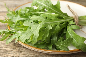 Bunch of fresh green arugula leaves on wooden table, closeup