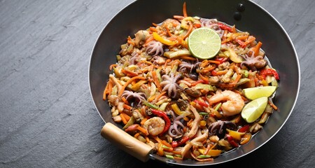 Stir-fry sea food in wok on grey textured table