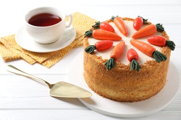 Delicious carrot cake, server and tea on white wooden table