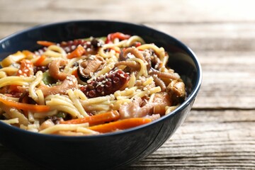 Stir-fry noodles with sea food and vegetables on wooden table, closeup
