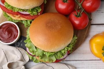 Delicious vegetarian burgers with chickpea cutlets, ingredients and sauce on white wooden table, flat lay