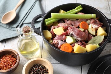 Cooking stew. Uncooked meat and vegetables in pot on white tiled table