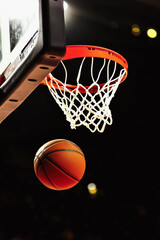 Fototapeta premium Vertical poster with a basketball flying into a basket, advertising a competition or an invitation to a game, concept of popularizing sports, and promotion of sports grounds in city squares