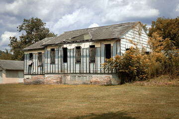Obraz premium Abandoned Weathered House in Overgrown Field