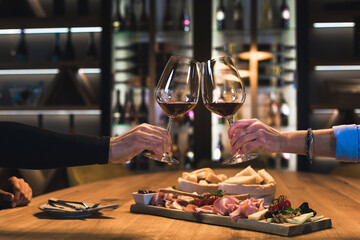 Smiling couple dining in a wine cellar room, enjoying fine white wine and delicious food