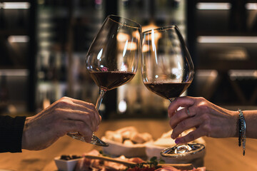 Smiling couple dining in a wine cellar room, enjoying fine white wine and delicious food