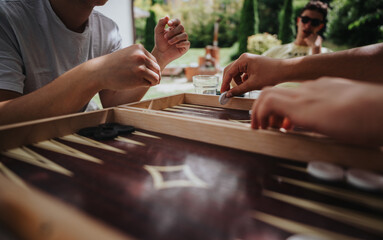 A group of friends playing backgammon outdoors, enjoying leisure time together in a garden on a sunny day. The scene captures friendship, relaxation, and strategic thinking.