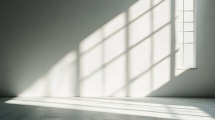 Obraz premium Natural light streams into a simple room through a minimalist window, creating striking shadows across the smooth wall, enhancing the tranquil atmosphere