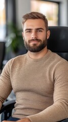 Fototapeta premium A young man in a beige sweater sits confidently at his desk, ready to tackle daily tasks in an inviting office
