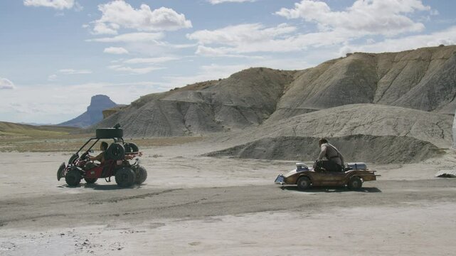 Cinematic wide shot of man leaping between moving karts in desert