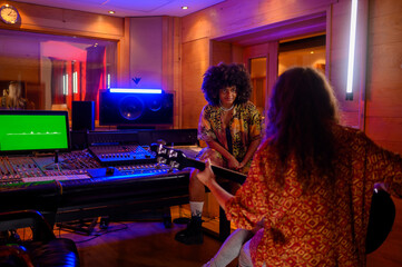 Latino woman sitting on soundboard while working in a music studio