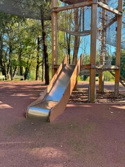 A playground slide set among trees with the image taken at a tilted angle